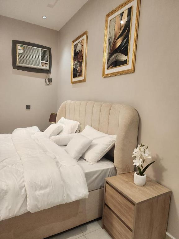a bedroom with a white bed and a table with flowers at ليالي القمر 2 in Sūq ath Thalut