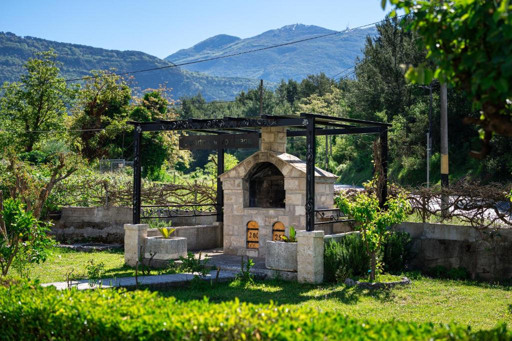 a small stone building in a garden with mountains in the background at Apartments Ivo Bozinovic in Tivat