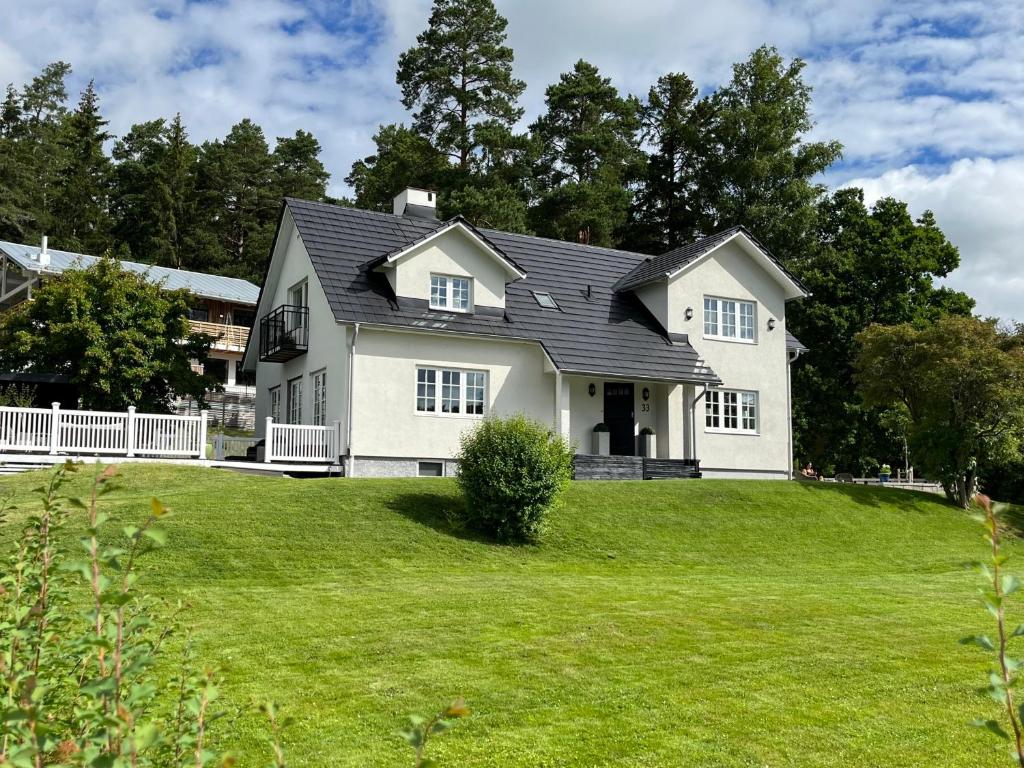 a white house on a hill with a green yard at Spacious, comfortable villa close to lake in Sigtuna