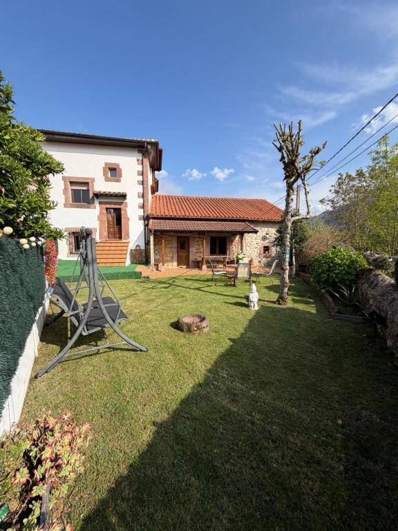 a yard with a house and a dog sitting in the grass at Casa Mayucu in Celis
