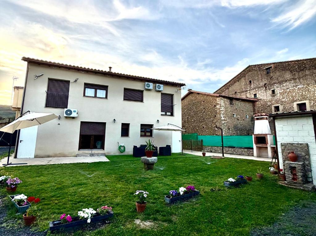 a large white house with a yard with flowers at Apartamentos rurales El Hondón del Lugar in Hoyos