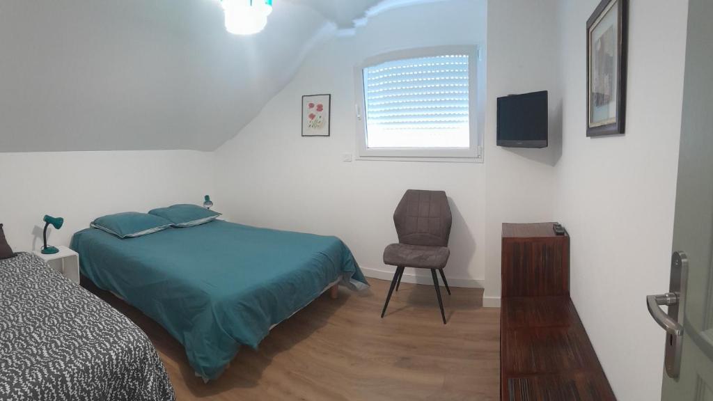 a bedroom with a bed and a chair and a window at Au château d'eau in Quintin