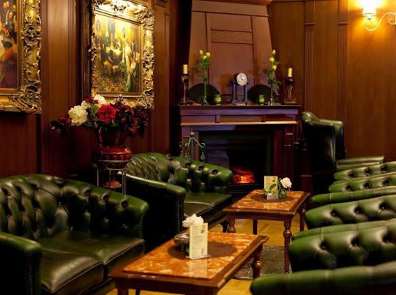 a living room with green leather furniture and a fireplace at Grand Hotel Residence Pieštany Adult only Boutique hotel Next to Wake Soul Beach in Piešťany