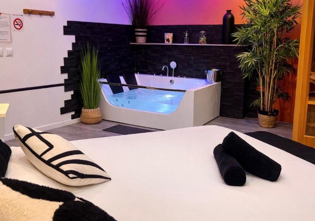 a bathroom with a tub and a bed with slippers at Spacieux spa et sauna in Bourges