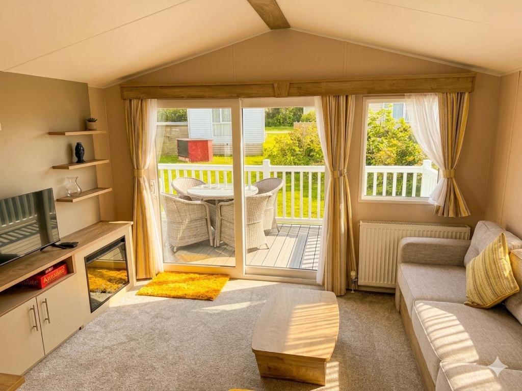 a living room with a couch and a tv and a balcony at Sun & Sand, Near Padstow, Seven Bays, Sleeps 6 in Saint Merryn