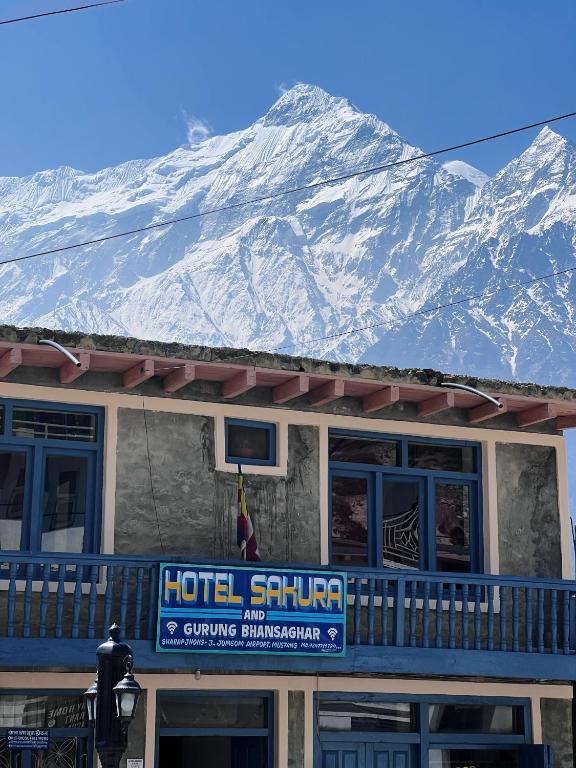 a hotel sign with a snow covered mountain in the background at Hotel Sakura in Jomsom