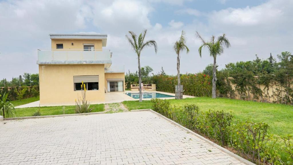 a house with a swimming pool and palm trees at villa Tarik with private pool in El Aïn