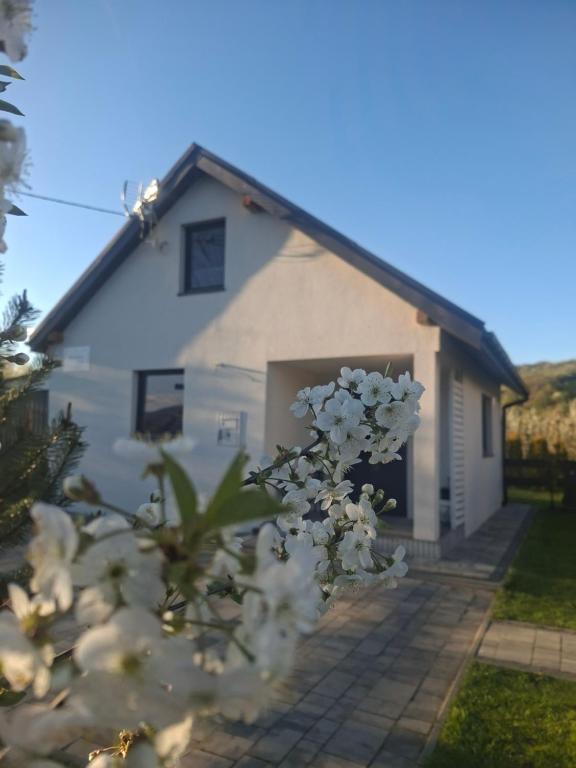 a white house with a door and some flowers at Domek na Podgrabiu in Łącko