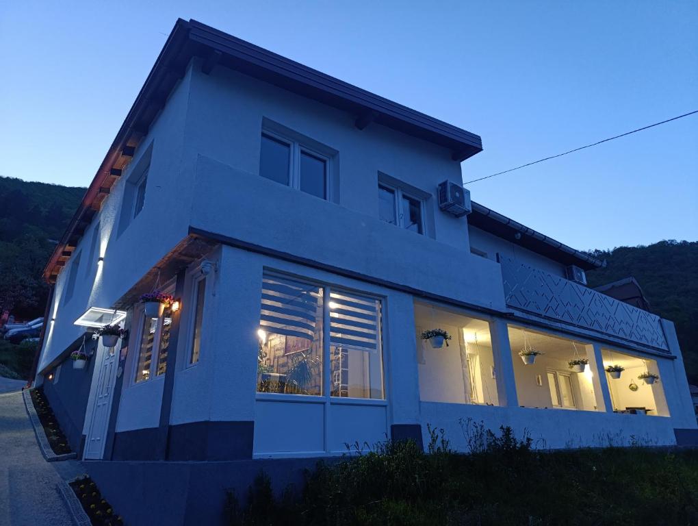 a white house with windows and lights on at Apartman Emma in Visoko