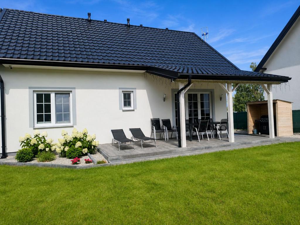 a white house with chairs and a patio at Domek Relaks pod Śnieżką in Miłków