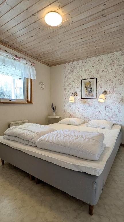 a large bed in a bedroom with a wooden ceiling at Rolig häst, Kaneeling Stugby AB in Dalskog