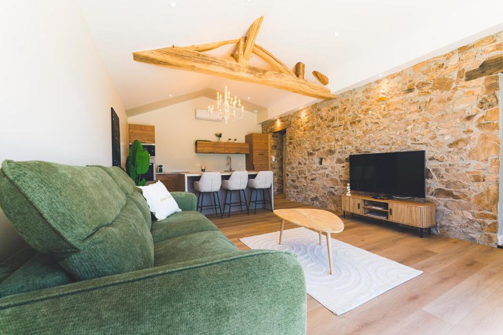 a living room with a green couch and a stone wall at Gîte de La Sulpicière - avec clim in Cholet