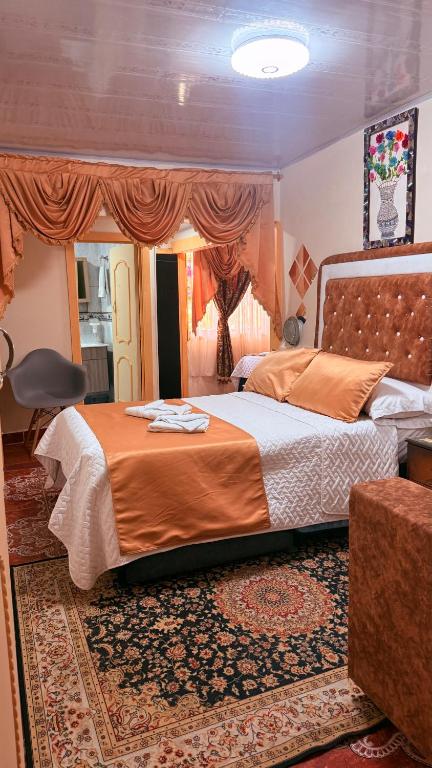 a bedroom with a large bed with an orange blanket at Posada Martha Tolima in Salento