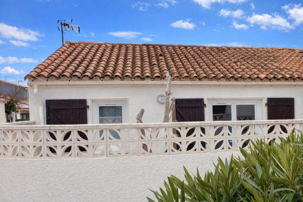 a white house with a fence in front of it at Anisades, Maison cosy avec jardin 5 min plage in Le Barcarès