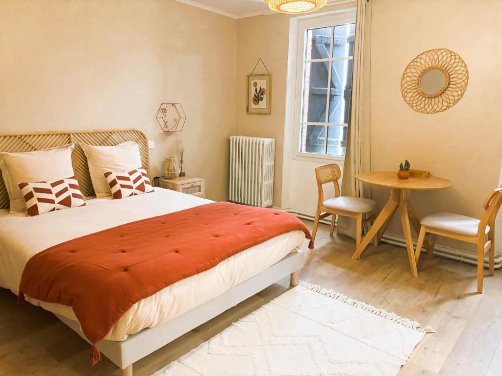 a bedroom with a bed and a table and a window at Le cottage du Breil in Verfeil