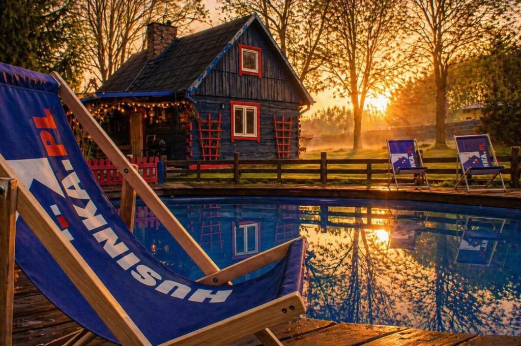 a house and a pool with a chair and a house at Agroturystyka Husinka pl in Husinka
