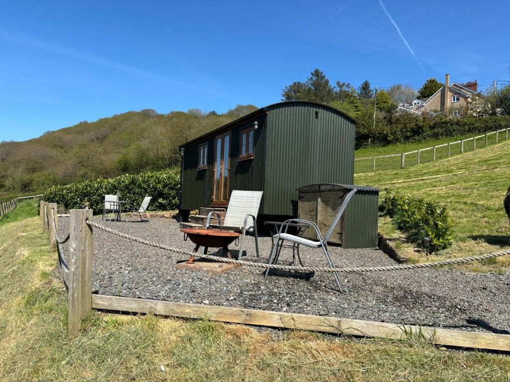 a group of chairs and a house in a yard at Fullabrook Farm Retreat, The Shepherdess Hut in West Down