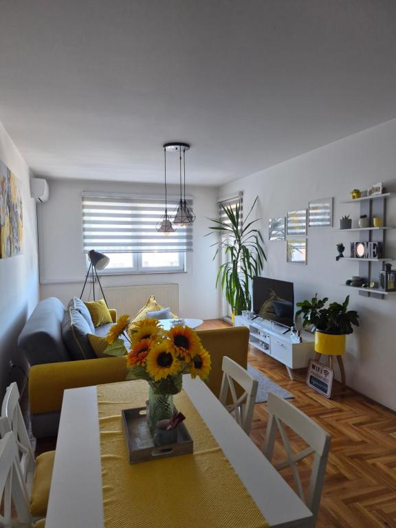 a living room with a couch and a table with flowers at Apartman M&S in Lukavica