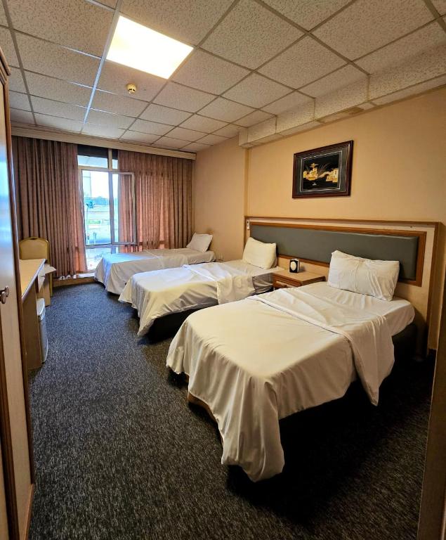 a hotel room with three beds in a row at HERSH Palace Hotel in Erbil