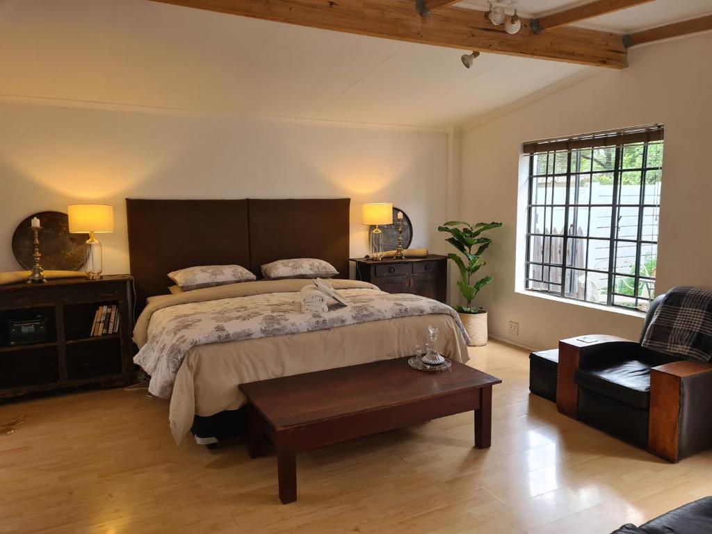 a bedroom with a large bed and a coffee table at Deco Cottage in Centurion