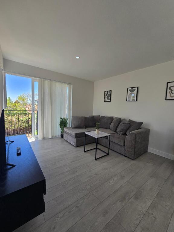 a living room with a couch and a table at Spacious 2BR with ensuite and AC unit and balcony near Heathrow in Cranford
