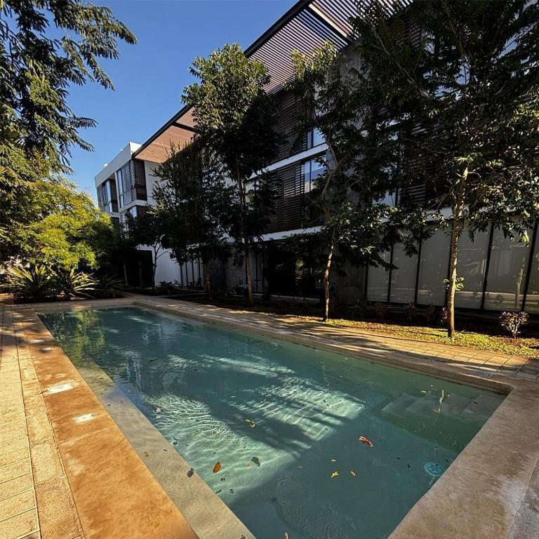 a swimming pool in front of a building at Departamentos Nütuuk in Mérida