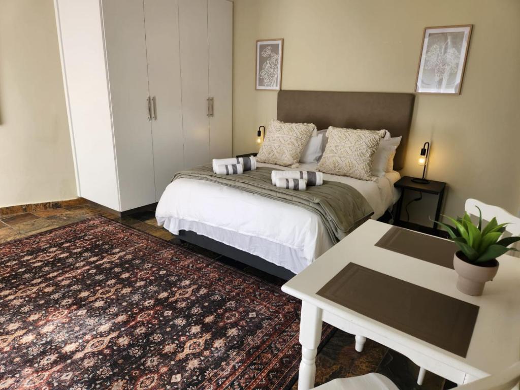 a bedroom with a bed with a table and a rug at The Studios on Smuts in Ermelo