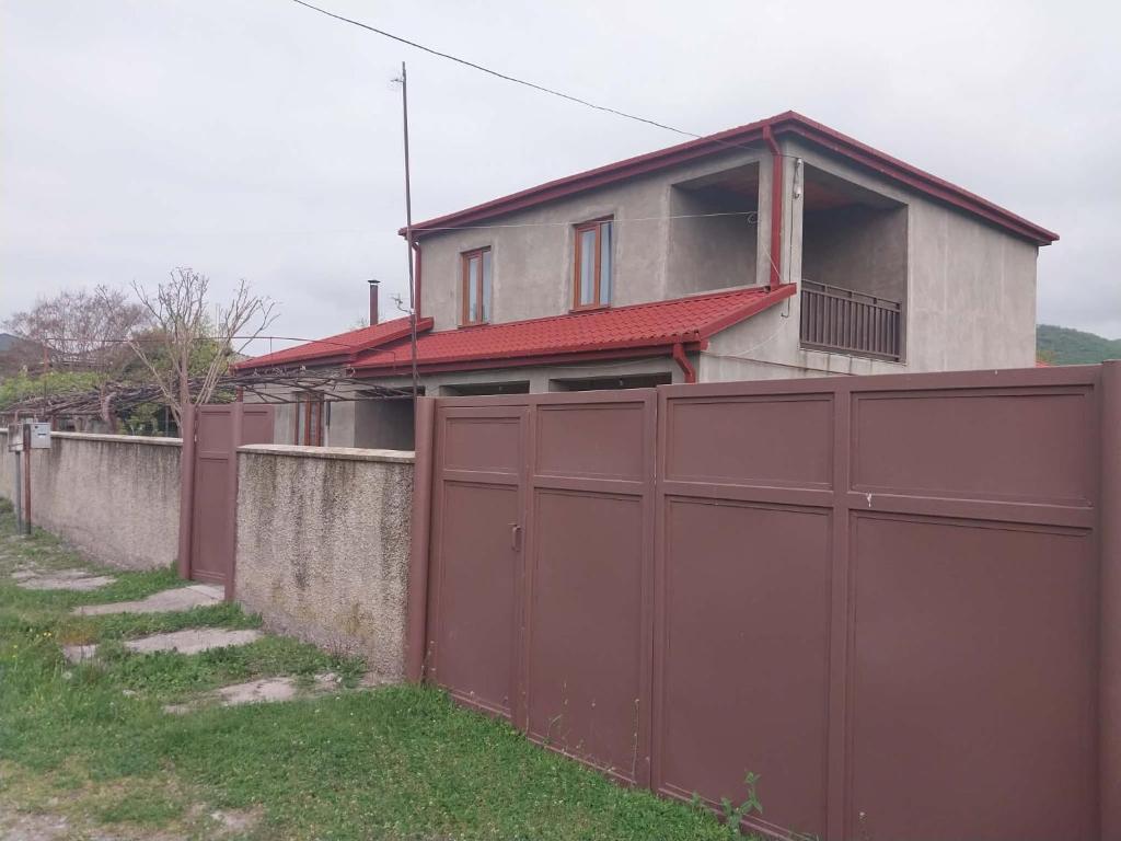 a house behind a fence with a red gate at Nia's Guesthouse in Zemo Alvani