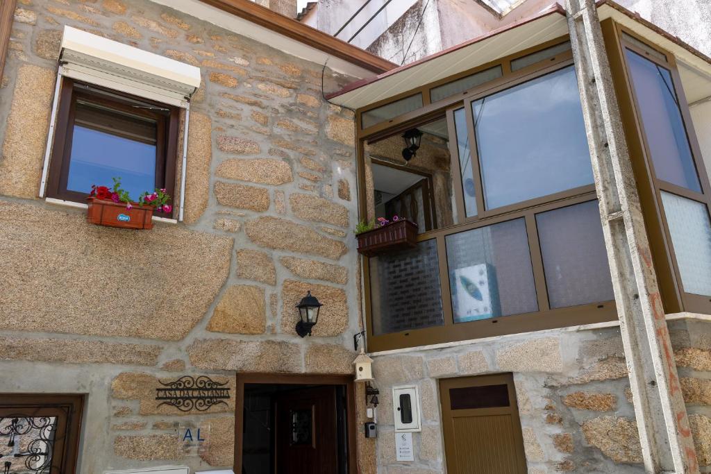 a stone building with windows and potted plants at Casa da Castanha Sernancelhe in Sernancelhe