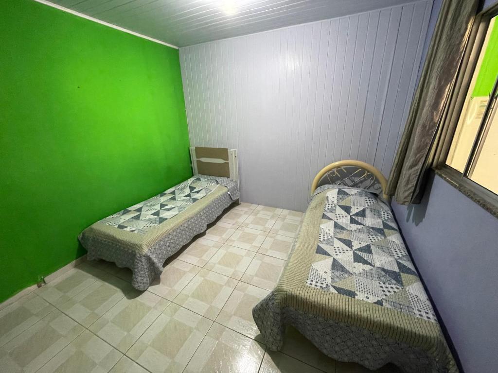 a room with two beds and a green wall at Hospedagem da Bela Quarto 4 Banheiro compartilhado in Caparaó Velho