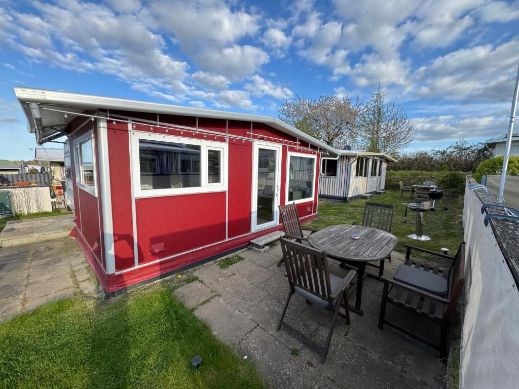 a red and white tiny house with a table and chairs at Campingurlaub Sehlendorf in Blekendorf