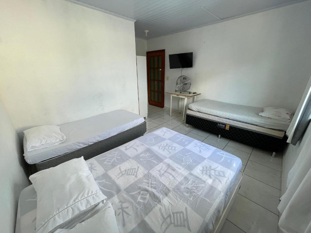 a room with two beds and a tv in it at Suites da Bela 05 Caparaó in Caparaó Velho
