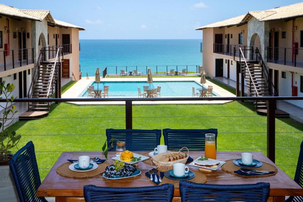a table with food and a view of the ocean at Coleção Falésias de Pipa- by Arcbio Experience in Pipa