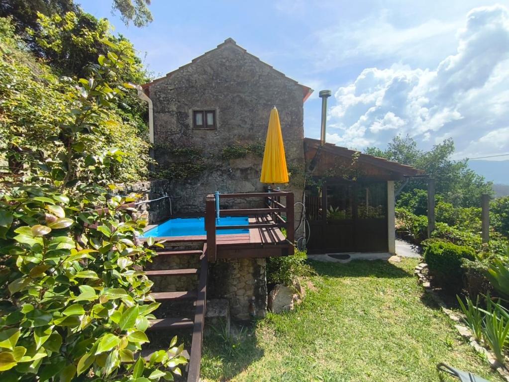 a house with a table and a yellow umbrella at Casa da Maria Gata in Sever do Vouga