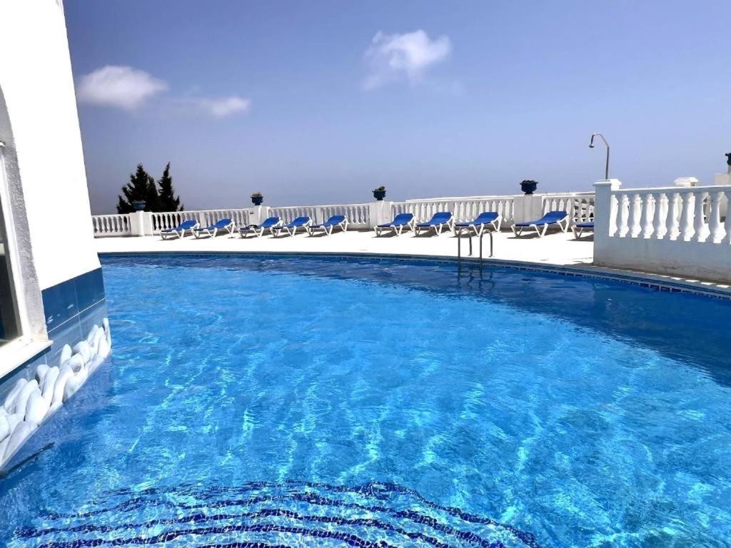 a large swimming pool with blue chairs and a building at Perlazul in Peniscola