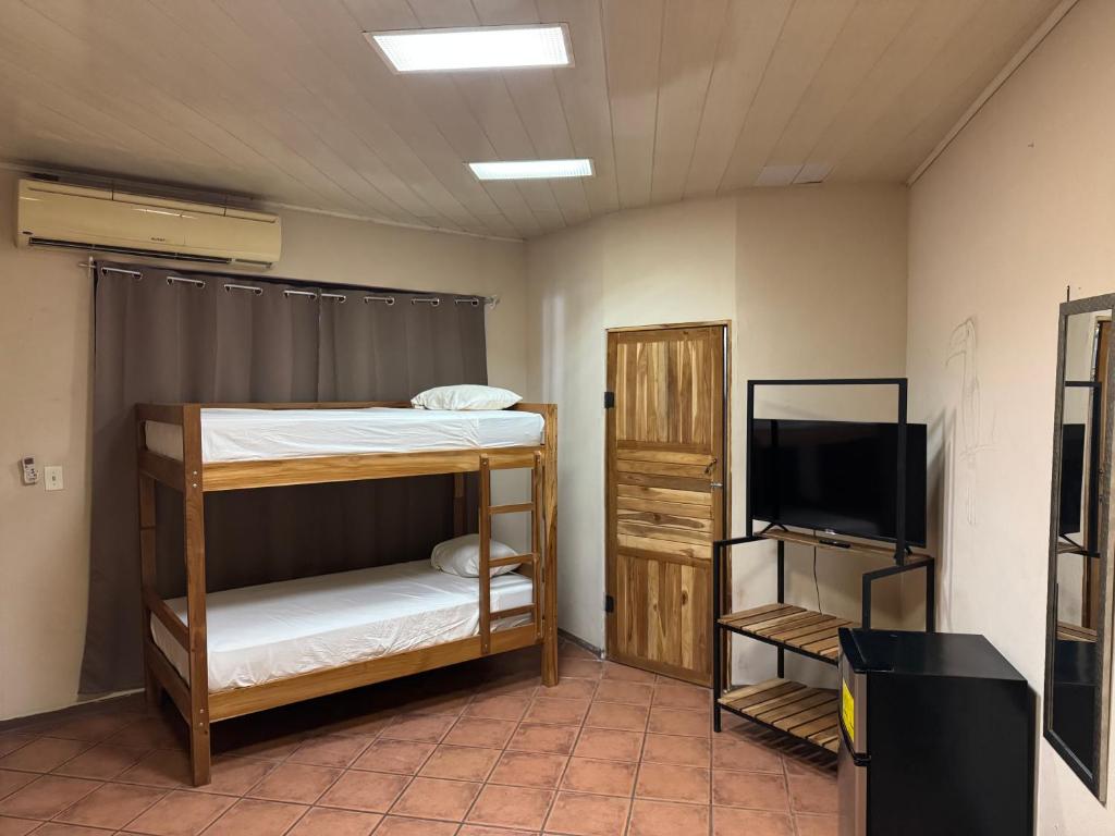 a room with a bunk bed and a flat screen tv at Aracari Stay in Quepos