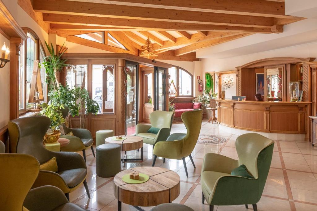 a lobby with green chairs and tables at Cavallino Lovely Hotel in Andalo