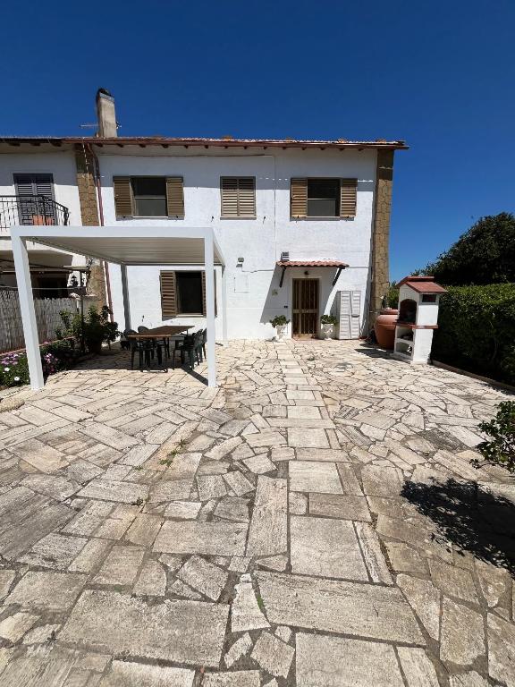 a stone patio in front of a white building at Il Quinto senso di Lù in Capalbio