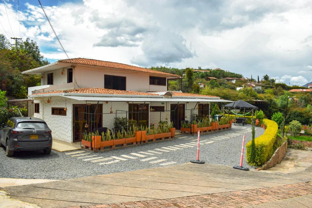 a house with a car parked in a parking lot at Posada Tierra Viva - Villa de Leyva in Villa de Leyva