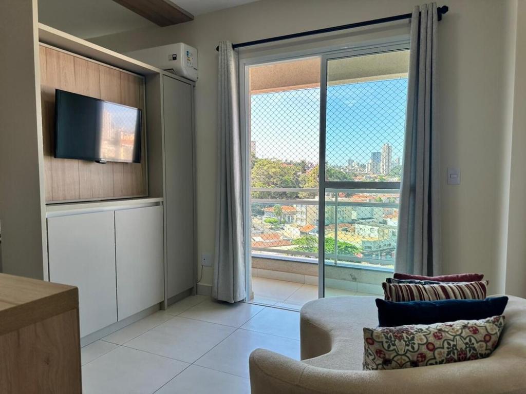 a living room with a couch and a large window at Apartamento 83 - Carmelo in Ribeirão Preto