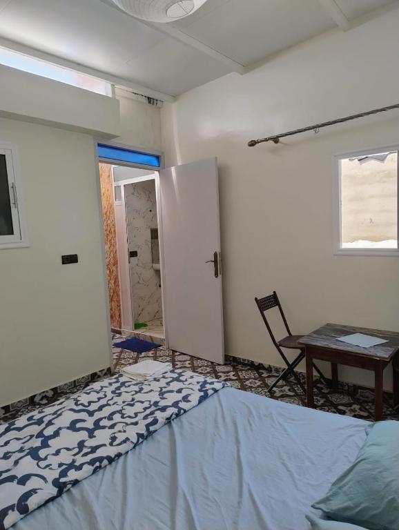 a room with a bed and a table and a chair at Tamraght samba 3 in Tamraght Ou Fella