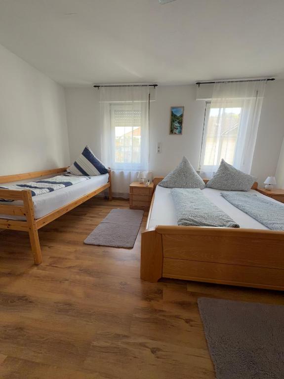 two beds in a room with wooden floors and windows at Dürschgangs Zimmer in Siegen