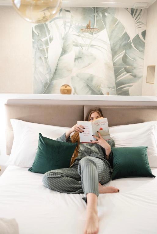 a woman laying on a bed reading a book at Dimora in Cortile in Manfredonia