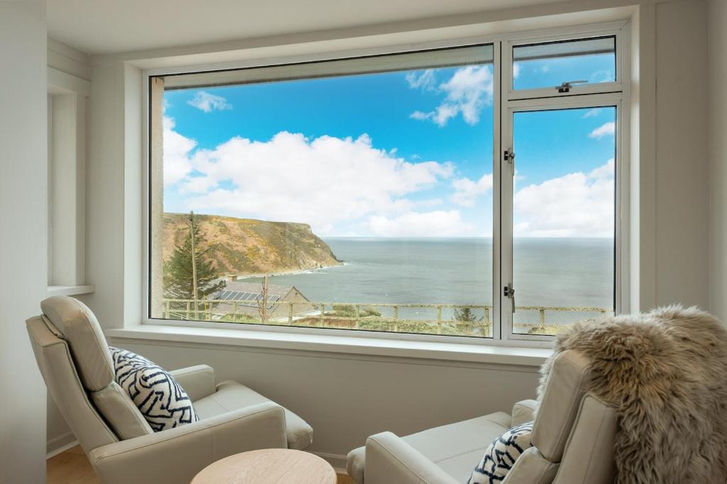 a living room with a large window looking out at the ocean at Murray Cottage in Gardenstown