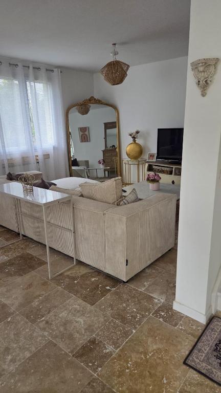 a living room with a couch and a mirror at pavillon en pleine nature in Brains-sur-Gée