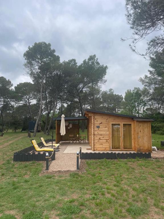 a small wooden cabin with a patio and a chair at Chalet Le Luc - Casa Zenitude in Le Luc