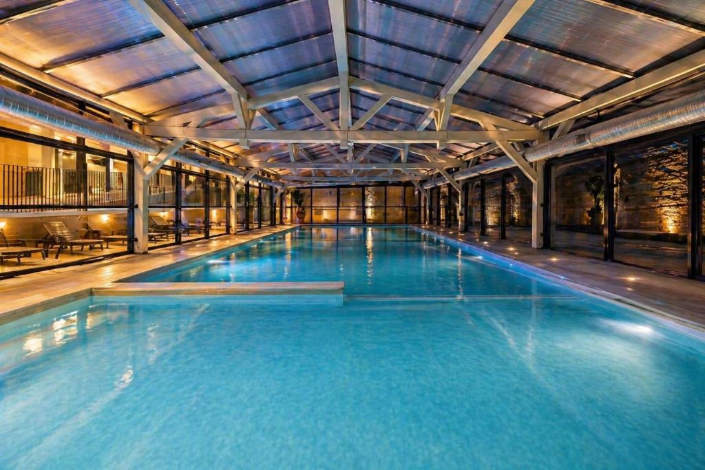 a large swimming pool with blue water in a building at Le Mazet du Mont Ventoux in Malaucène