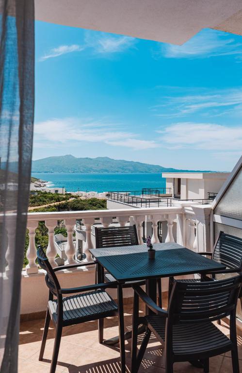 a table and chairs on a balcony with a view of the ocean at Parid Apartments in Sarandë
