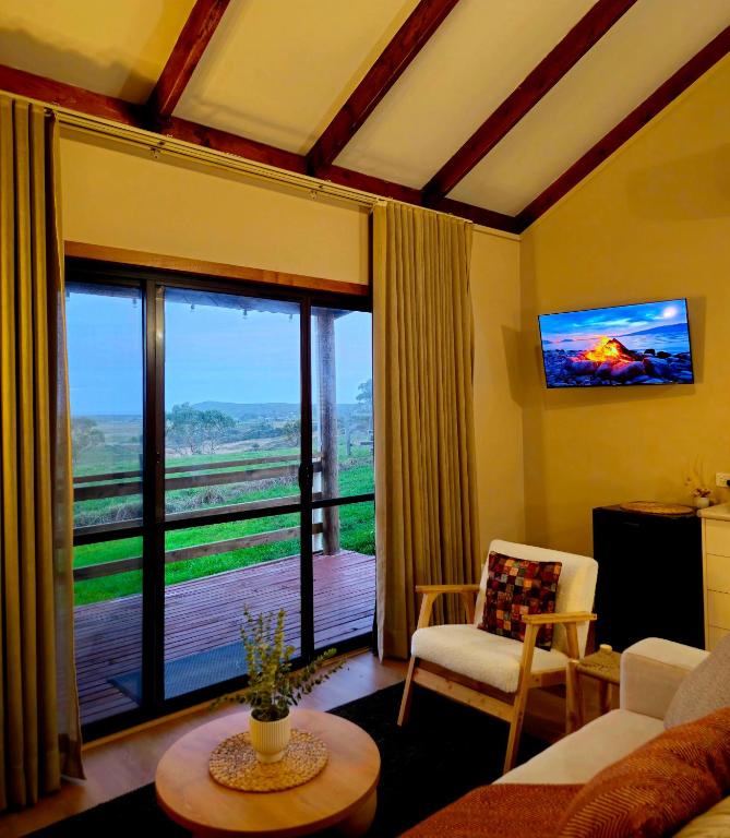 a living room with a couch and a large window at 12 Apostles Cottages - Tullarook in Princetown