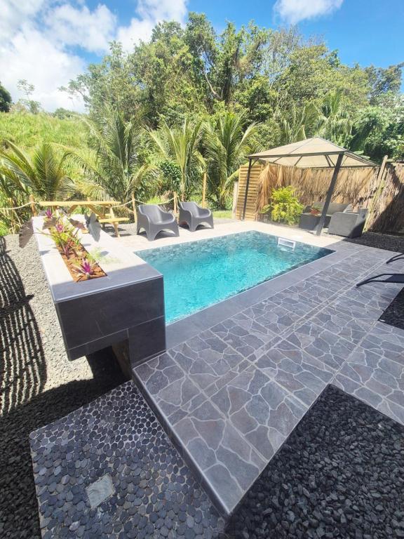 a swimming pool with chairs and a gazebo at L'Escale du Plaisir in Grande Savane